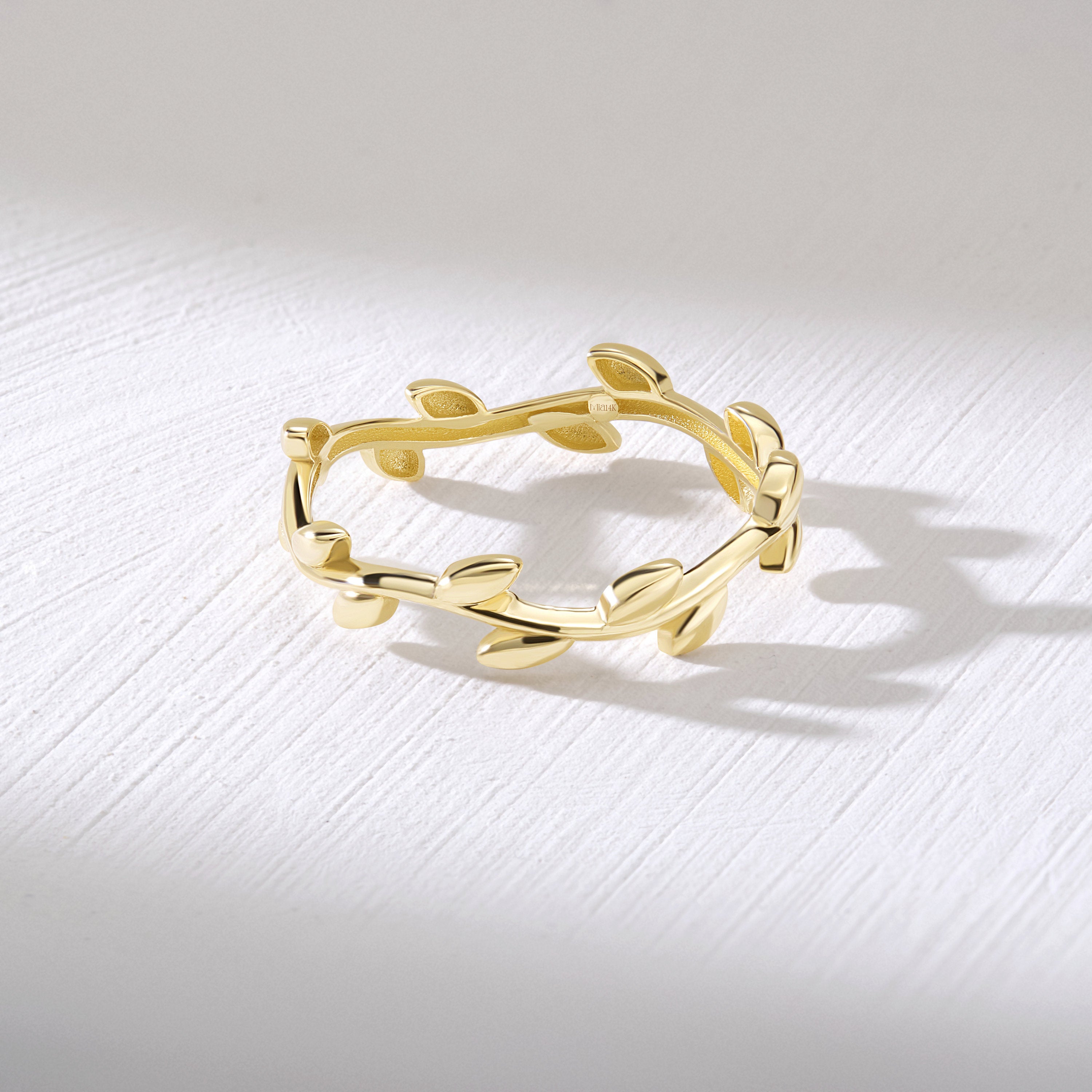 A solid gold wedding ring with a delicate leaf design. The ring has a simple, minimalist and elegant style.