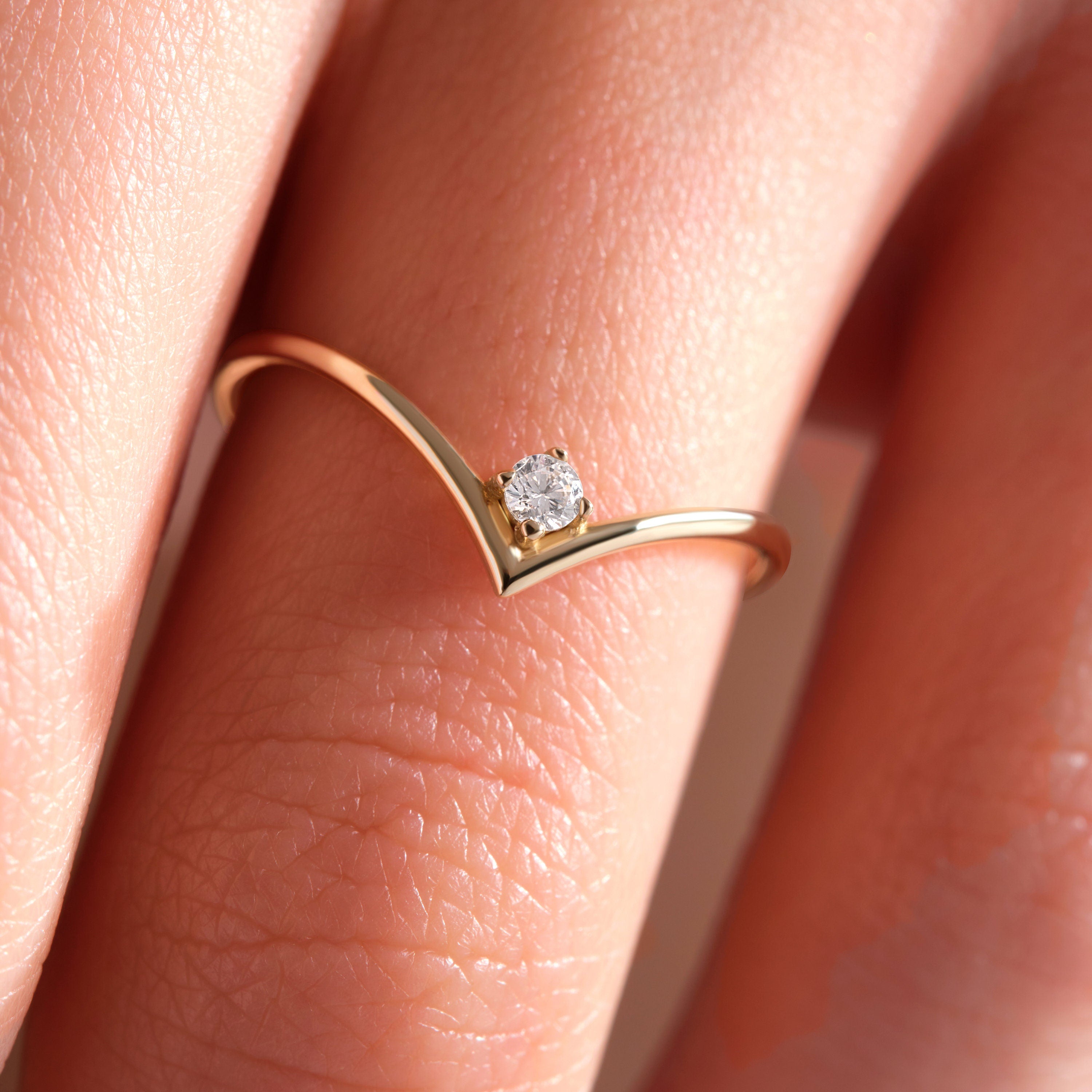 Solid Gold V Ring is a stacking wedding band that will fit nicely with your engagement ring. With a dainty simulated diamond, this chevron wedding band has a curved wishbone style and can be classified as a contour band or minimal nesting ring.