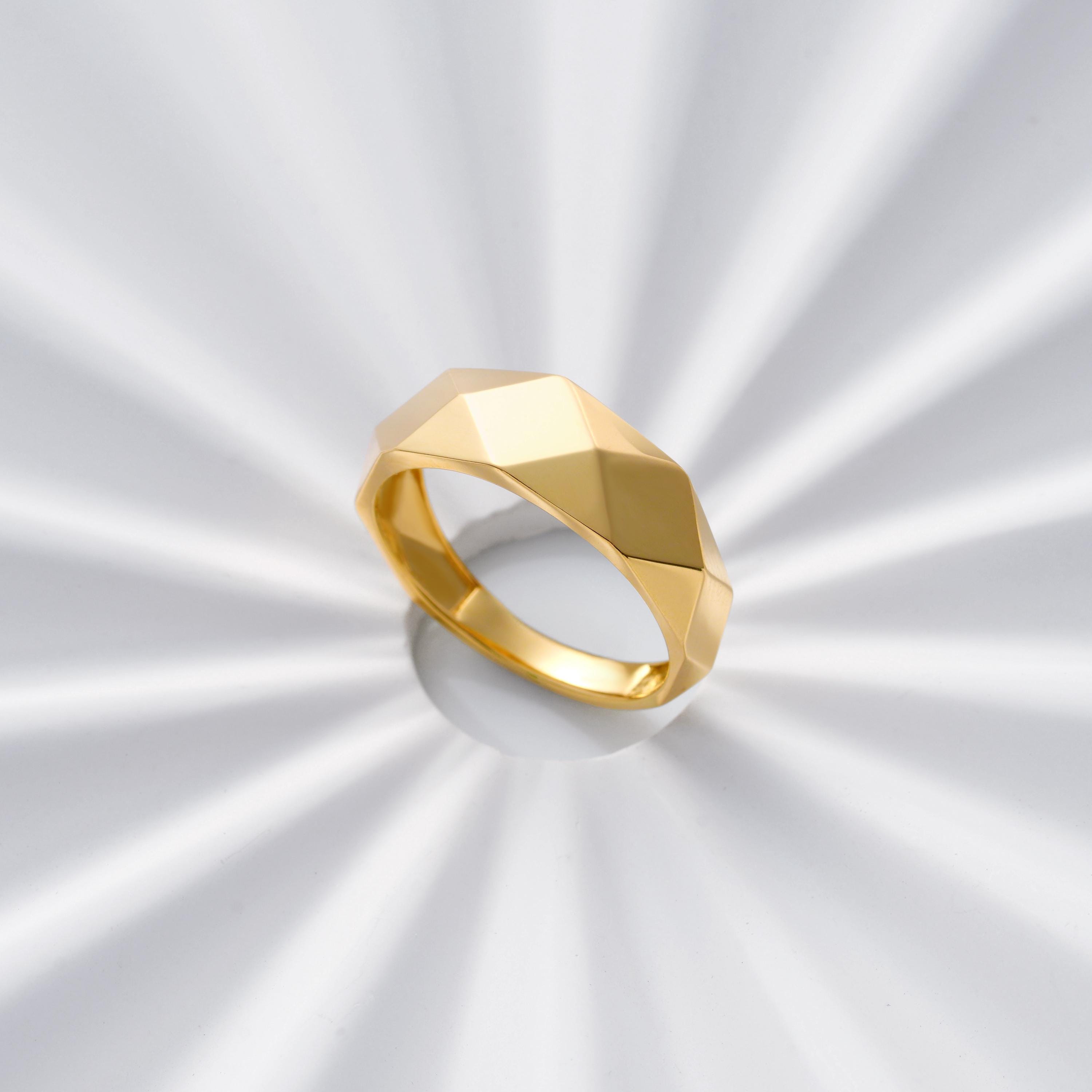 Studio shot of faceted solid gold band ring