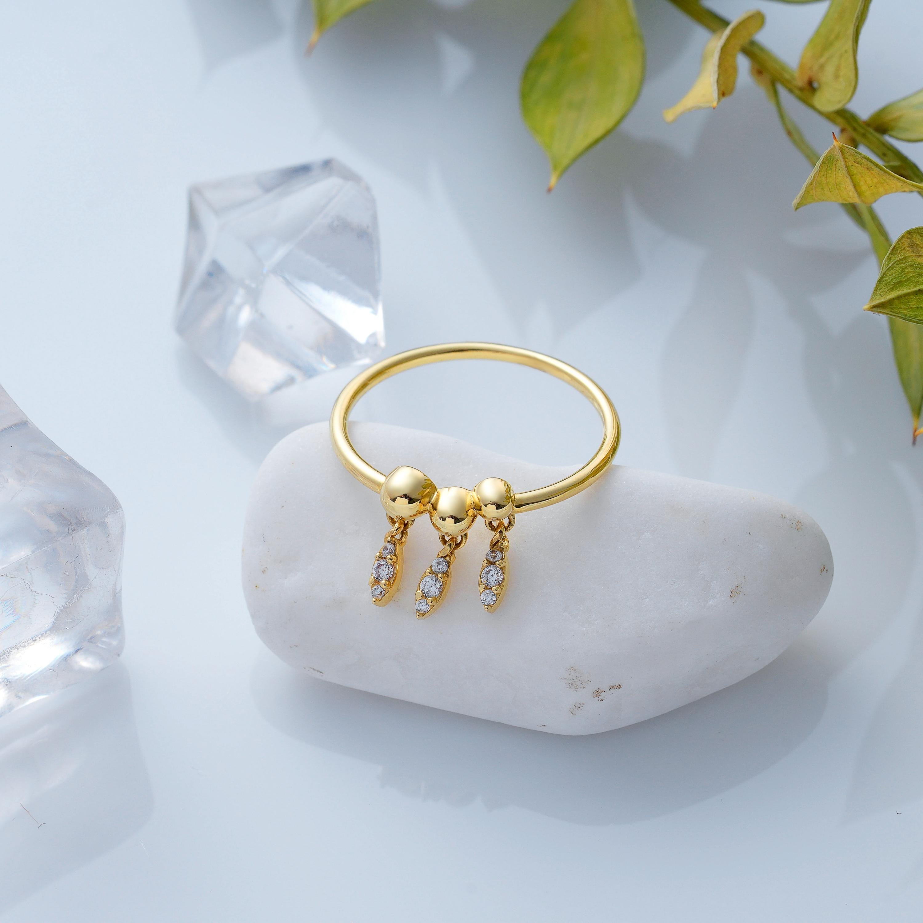 solid gold round band ring with bead accents and dangling pave diamond drop charms