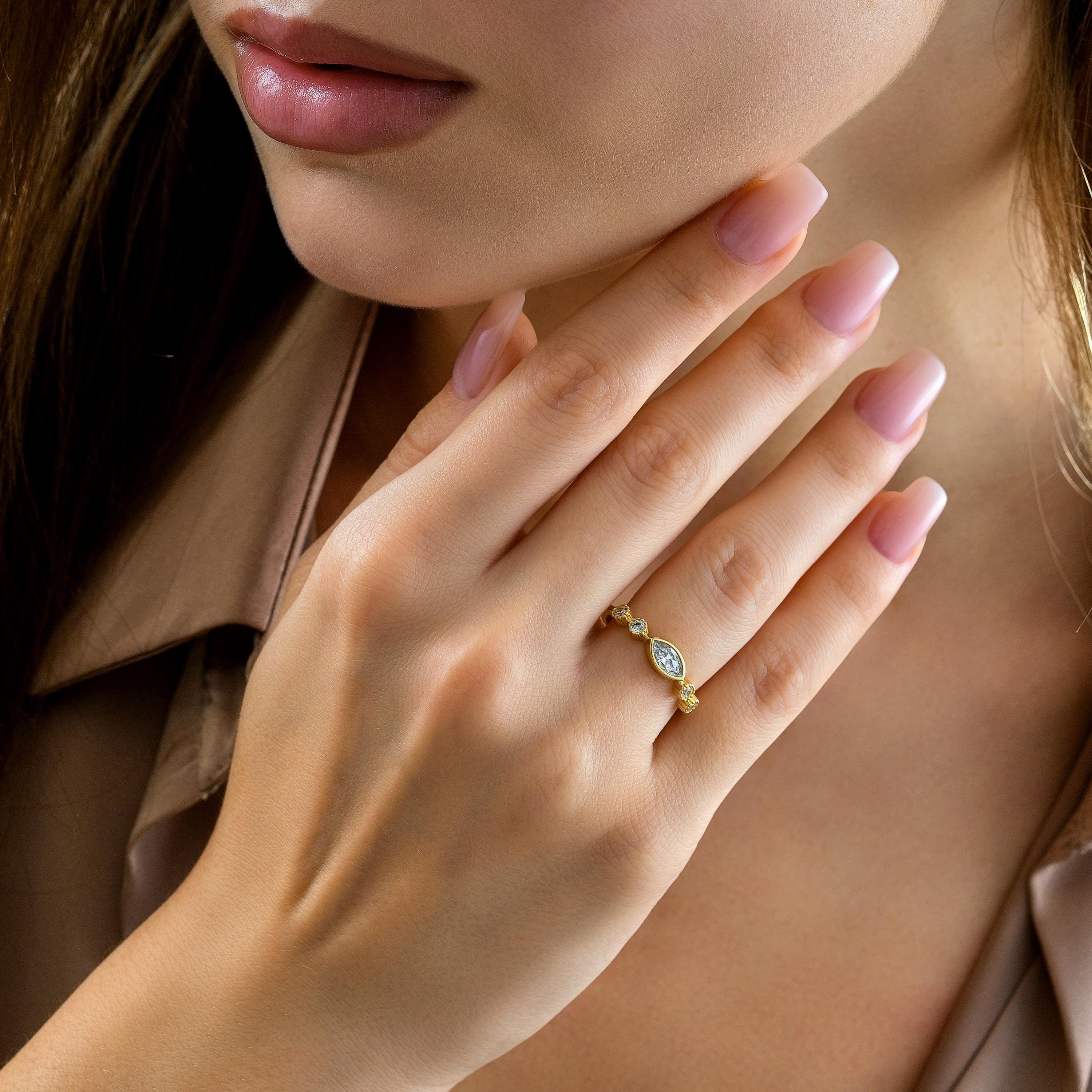marquise bezel gold ring on finger, showing bezel frame and round accent stones