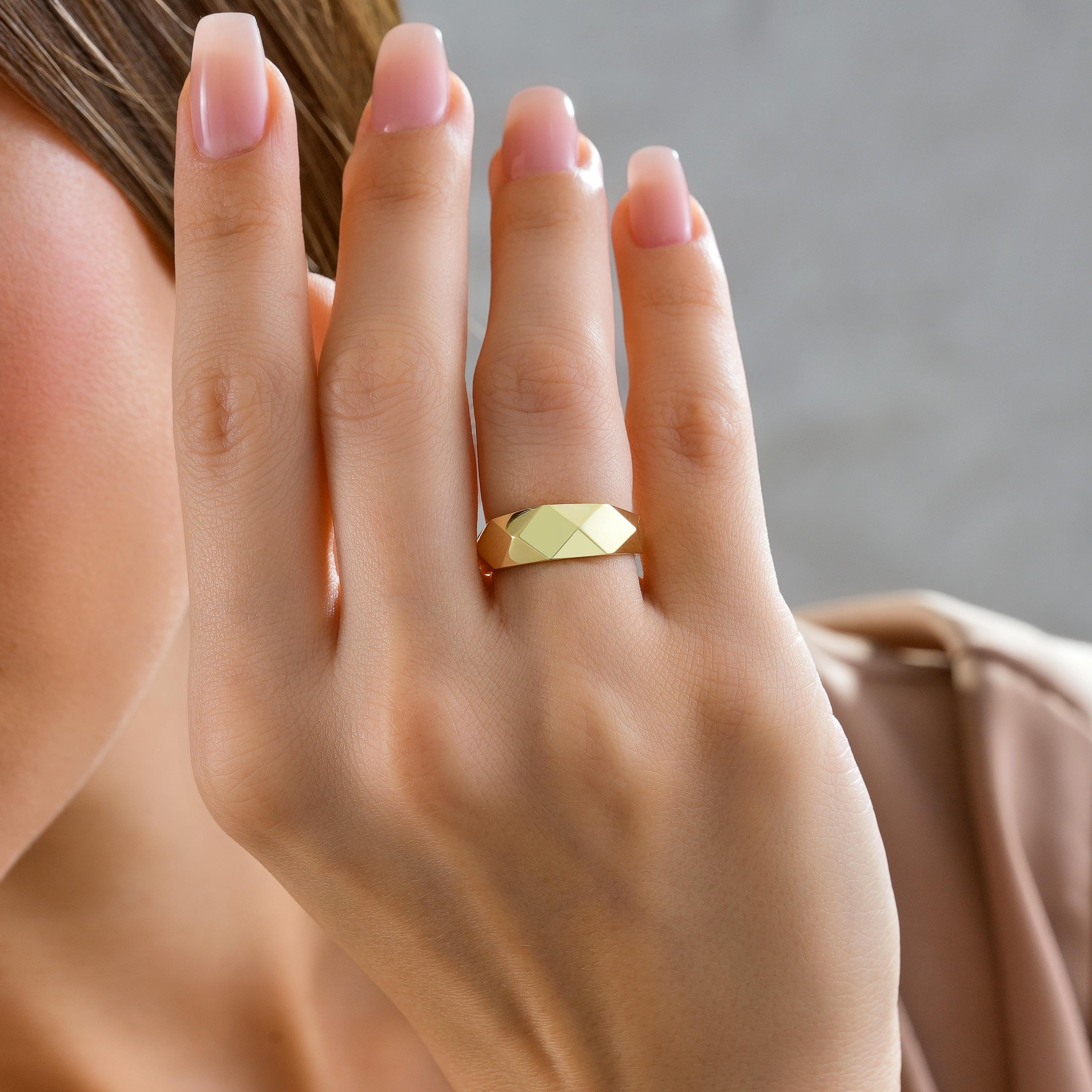 Solid gold faceted geometric band ring worn on hand