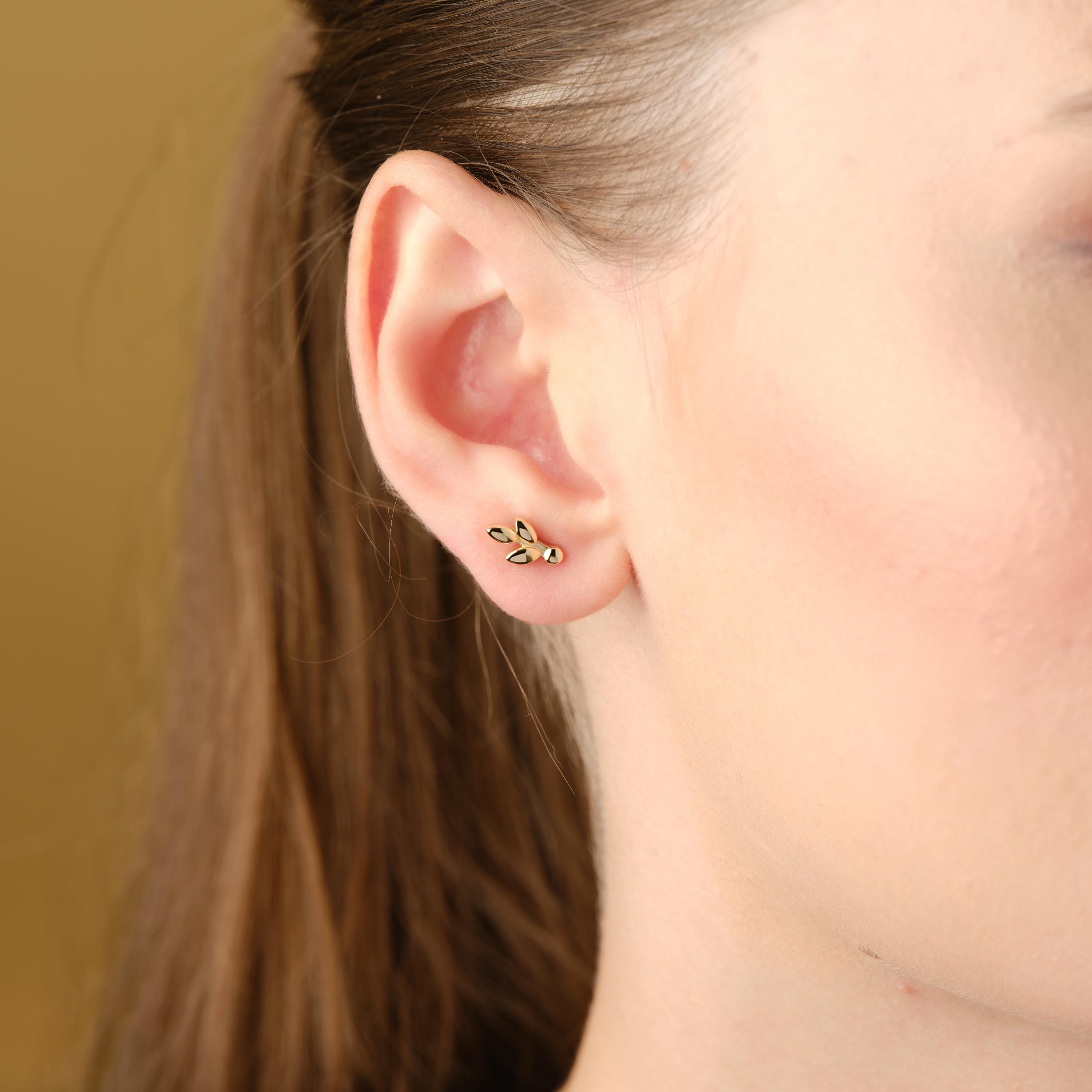 Leaf cluster gold stud worn on ear.